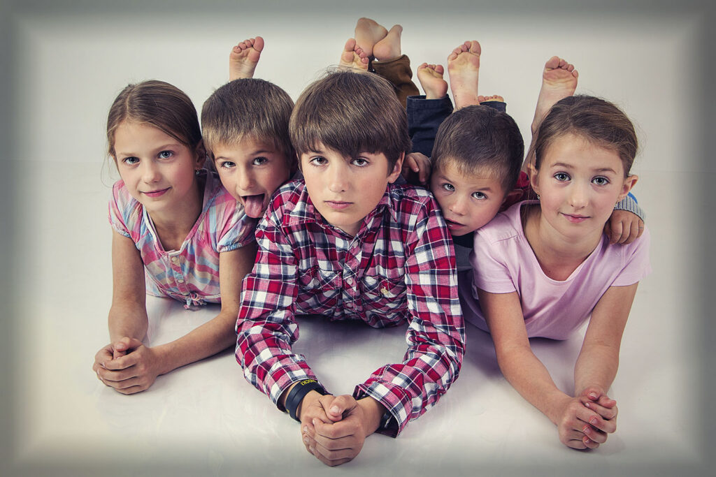 Skupinová fotografie dětí ležících vedle sebe v ateliéru