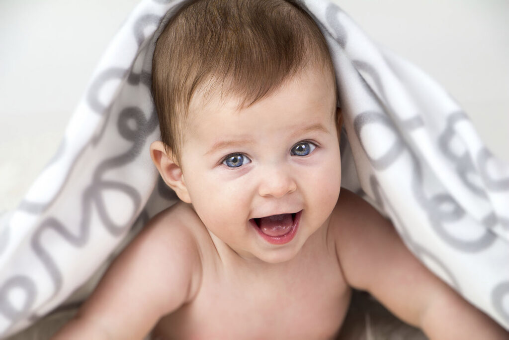 Usměvavé miminko zabalené v dece při focení v ateliéru