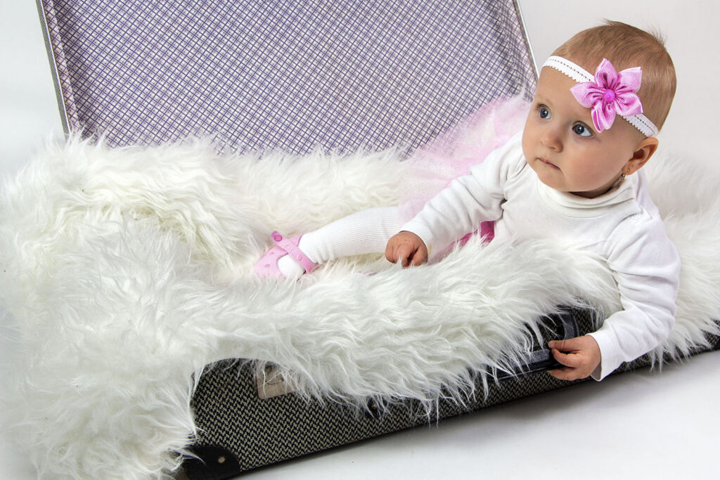 Miminko – holčička s čelenkou ležící na měkké dece v ateliéru