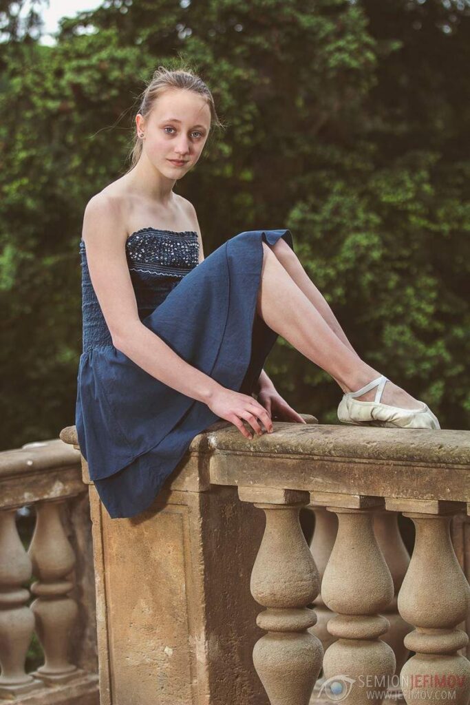 Dívka sedící na kamenném zábradlí – portrétní focení v exteriéru