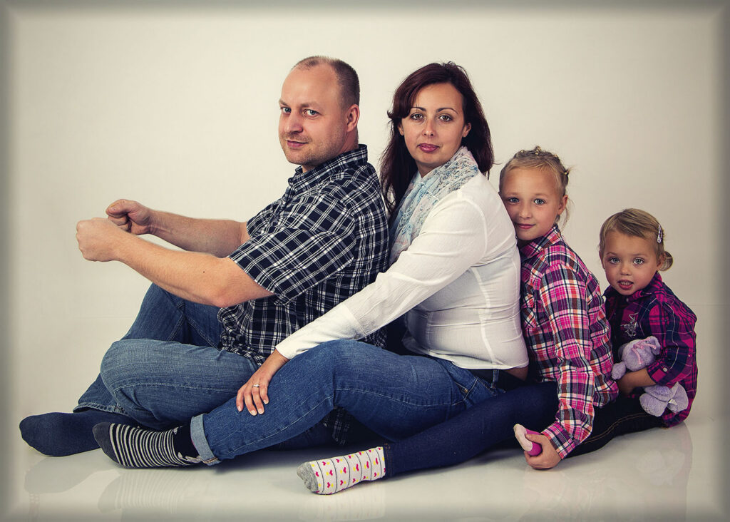 Rodinný portrét čtyřčlenné rodiny sedící vedle sebe v ateliéru